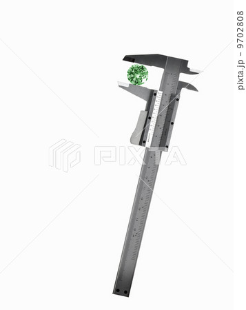 A caliper or guage measuring a green cyrstal cut gemstone. A caliper or guage measuring a green cyrstal cut gemstone. 9702808