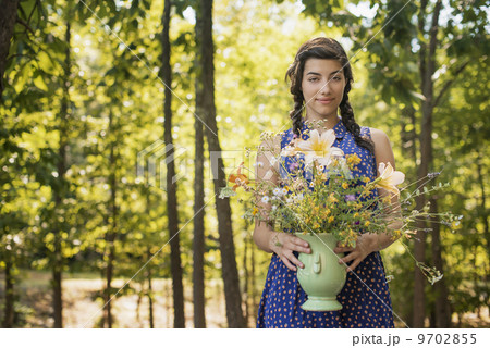 A young woman holding a vase of flowers. A young woman holding a vase of flowers. 9702855