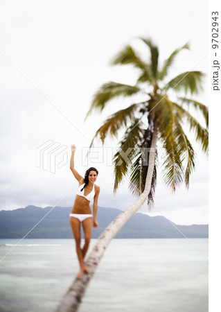 A woman balancing on a leaning palm tree in Las Galeras, Samana Peninsula, Dominican Republic. 9702943