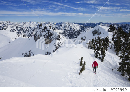 A climber in a red jacket on the summit of Snoqualmie Peak in the Cascades range of mountains in Washington state, USA. A climber in a red jacket on the summit of Snoqualmie Peak in the Cascades range of mountains in Washington state, USA. 9702949
