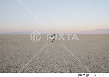 Man with camera and tripod on the flat saltpan or playa of Black Rock desert, Nevada. 9702968