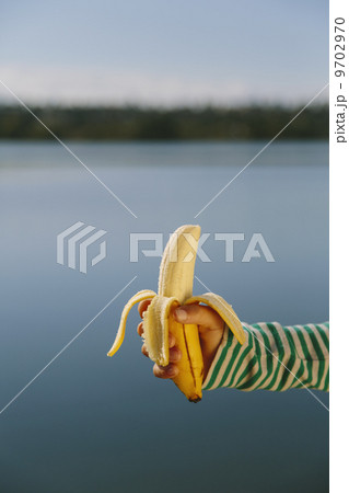 Nine year old girl holding organic, peeled banana 9702970