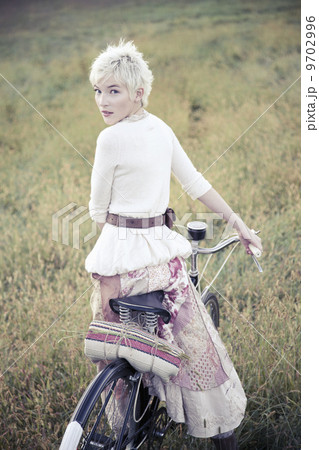 A girl in vintage clothing, paisley patterned cotton skirt with a bicycle in long grass. A girl in vintage clothing, paisley patterned cotton skirt with a bicycle in long grass. 9702996