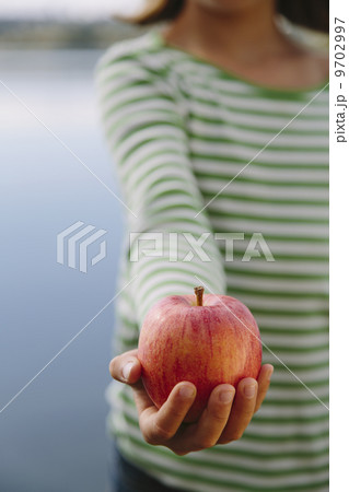 Detail of nine year old girl holding organic apple 9702997