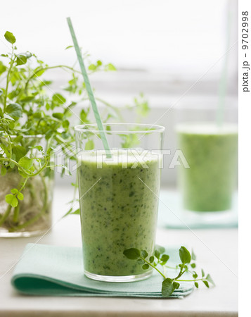 Two glasses of a healthy green smoothie herb drink with a straw. 9702998