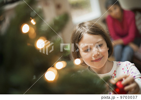 A girl placing a handmade ornament on a Christmas tree. A girl placing a handmade ornament on a Christmas tree. 9703037
