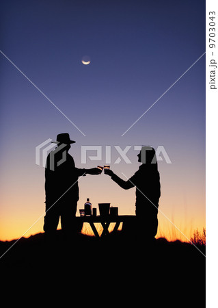 Guests at Wolwedans at sunset. Silhouette of two people, a couple, raising glasses in a romantic toast in NamibRand Nature Reserve, Namibia. Guests at Wolwedans at sunset. Silhouette of two people, a couple, raising glasses in a romantic toast in NamibRand Nature Reserve, Namibia. 9703043