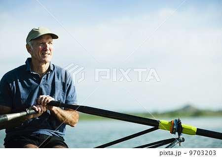 A middle-aged man rowing a single scull rowing boat on the water. A middle-aged man rowing a single scull rowing boat on the water. 9703203
