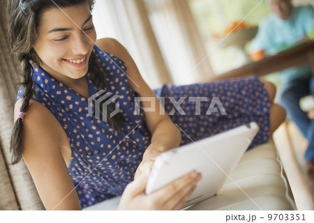 A young woman in a traditional home using an electronic personal notepad computer. A young woman in a traditional home using an electronic personal notepad computer. 9703351