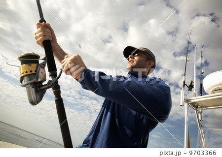 A man on a boat holding a fishing rod. 9703366