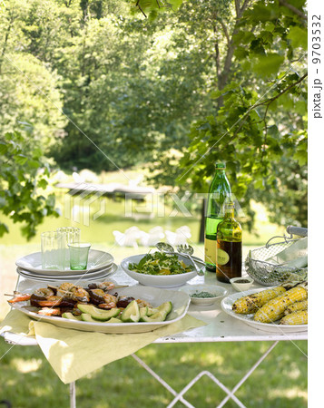 A buffet table set up in a garden for al al fresco meal. Salads and prepared food dishes. A buffet table set up in a garden for al al fresco meal. Salads and prepared food dishes. 9703532