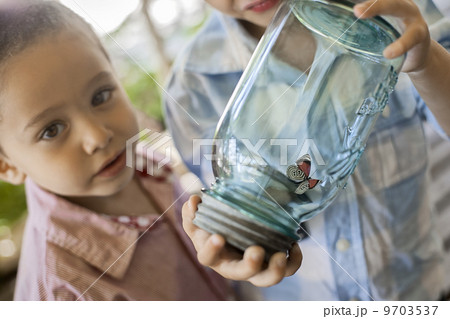 A child holding a glass jar and examining a butterfly. A child holding a glass jar and examining a butterfly. 9703537