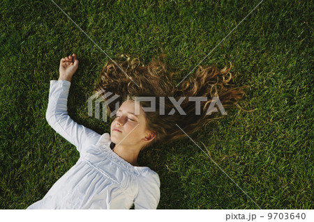 Nine year old girl smiling and resting on field of lush, green grass Nine year old girl smiling and resting on field of lush, green grass 9703640