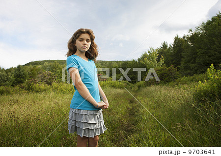 A young girl standing by a path through the long grass in a field. A young girl standing by a path through the long grass in a field. 9703641