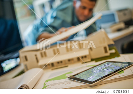Architects working on a green construction project, using computer technology, in an office. An architect's model of a house. Computer tablet. 9703652