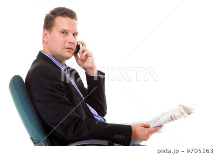 young businessman reads newspaper while phoning 9705163