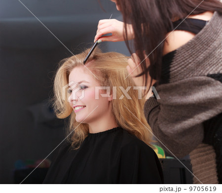 Hairstylist combing female client blond girl in hairdressing salon Hairstylist combing female client blond girl in hairdressing salon 9705619