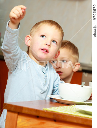 Two brothers boys kids children eating corn flakes breakfast morning meal at home. 9706670