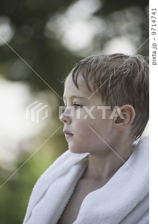 A young boy with wet hair, wrapped in a towel after swimming. A young boy with wet hair, wrapped in a towel after swimming. 9714741