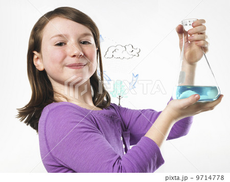 A young girl holding a conical flask of blue liquid in front of an evaporation cycle illustration on a clear surface.  9714778