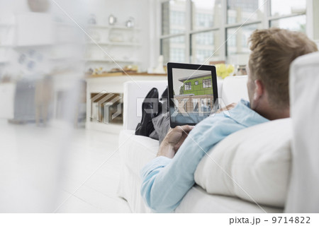 Business people. The office in summer. A man lying on a sofa, in comfort, in a quiet airy office environment. Using a digital tablet. Business people. The office in summer. A man lying on a sofa, in comfort, in a quiet airy office environment. Using a digital tablet. 9714822