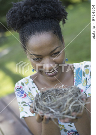 A woman holding a bird nest in her hands.  9714954