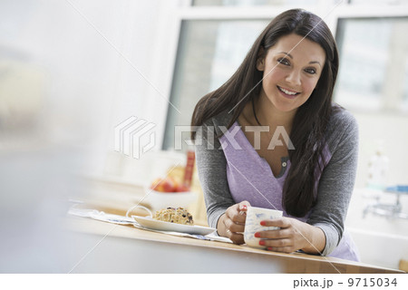 An office or apartment interior in New York City. A young woman with long black hair, having a cup of coffee. An office or apartment interior in New York City. A young woman with long black hair, having a cup of coffee. 9715034