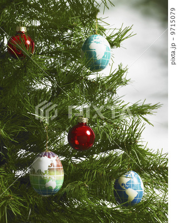 Still life. Green leaf foliage and decorations. A pine tree branch with green needles. Christmas decorations. A small group of red and blue tree ornaments. Oblong shapes with continents outlined on a blue background. Still life. Green leaf foliage and decorations. A pine tree branch with green needles. Christmas decorations. A small group of red and blue tree ornaments. Oblong shapes with continents outlined on a blue background. 9715079