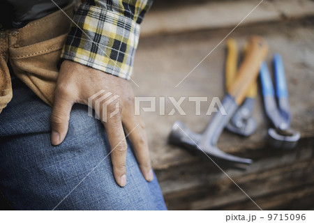 A reclaimed lumber workshop. A person at a workbench, and tools, grippers and pliers lined up on a plank of wood.  9715096