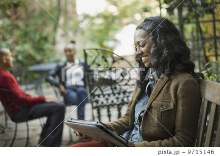 Scenes from urban life in New York City. A group of people sitting on a terrace outdoors. A woman using a computer tablet or pad.  9715146