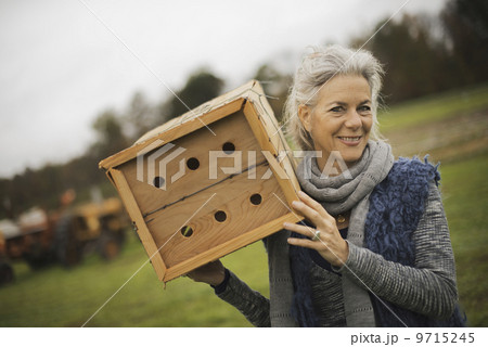 Organic Farmer at Work. A woman holding a bug box, a wooden box with holes for insects to nest in. Organic Farmer at Work. A woman holding a bug box, a wooden box with holes for insects to nest in. 9715245