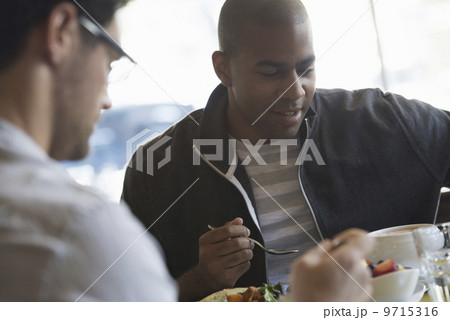 Business people in the city. Keeping in touch on the move. Two men seated at a cafe table, having a meal.  9715316