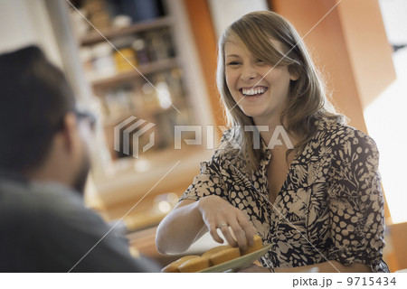 A couple sitting in a coffeeshop smiling and talking over a cup of coffee. 9715434