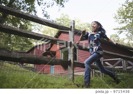 A farm paddock fence. A young girl running around. A farm paddock fence. A young girl running around. 9715436