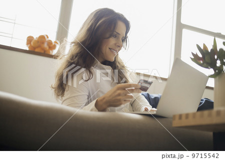 Woman on-line shopping on laptop on sofa with credit card 9715542