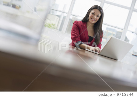 Business people. The office in summer. A young woman sitting comfortably in a quiet airy office environment. Using a laptop. 9715544