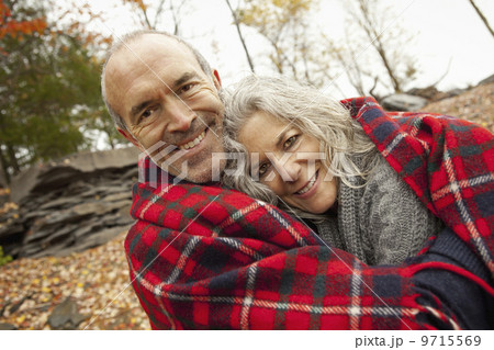 A couple, man and woman on a day out in autumn. Sharing a picnic rug to keep warm. A couple, man and woman on a day out in autumn. Sharing a picnic rug to keep warm. 9715569
