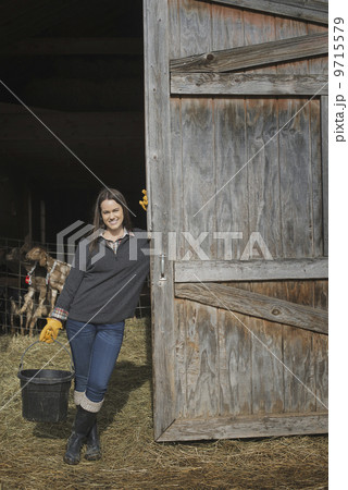 A small organic dairy farm with a mixed herd of cows and goats.  Farmer working and tending to the animals. 9715579