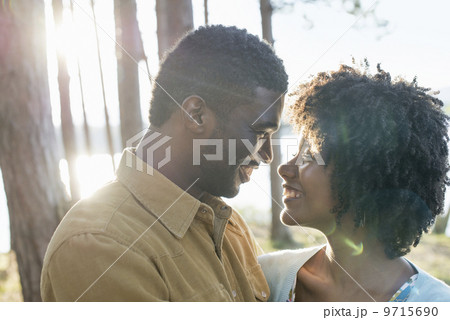 A happy couple in a shady spot in woodland in summer. Hugging and holding each other.  9715690