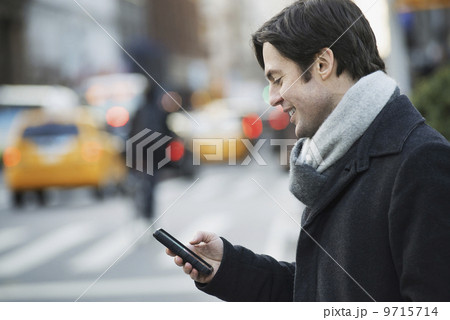 Man on busy street with smartphone 9715714
