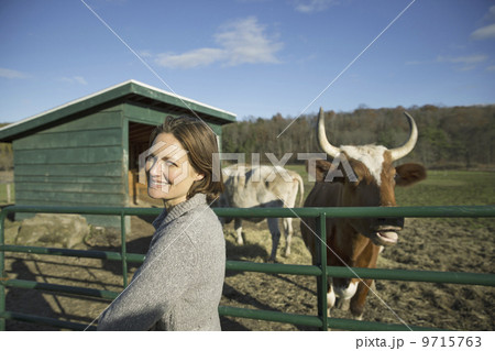 Animal sanctuary. A woman beside the fence, feeding two cows. 9715763