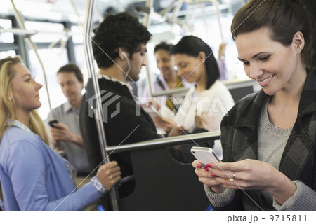 New York City park. People, men and women on a city bus. Public transport. Keeping in touch. A young woman checking or using her cell phone. 9715811