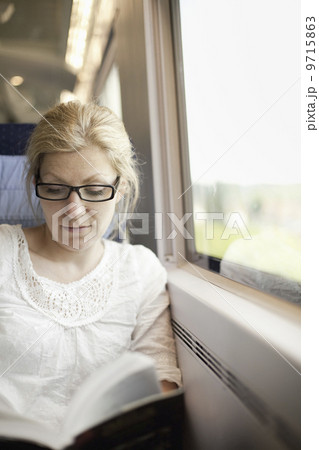 A woman sitting by a train window, reading a book. A woman sitting by a train window, reading a book. 9715863