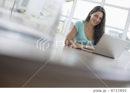 Business people. The office in summer. A young woman sitting comfortably in a quiet airy office environment. Using a laptop. 9715892