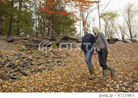 A couple, man and woman on a day out in autumn walking through fallen leaves. Holding hands. A couple, man and woman on a day out in autumn walking through fallen leaves. Holding hands. 9715963