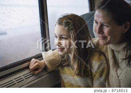 A man and a young girl sitting beside the window in a train carriage looking out at the countryside. Smiling in excitement. 9716015