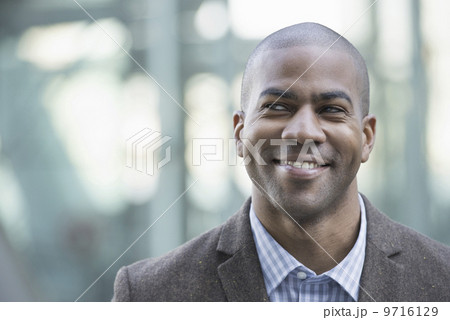 Business people in the city. Keeping in touch on the move. A man in jacket and tie smiling and looking into the distance.  9716129