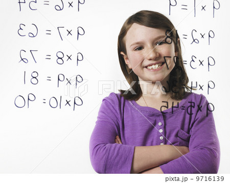 A child looking at a series of multiplication tables written on a see through surface. A child looking at a series of multiplication tables written on a see through surface. 9716139