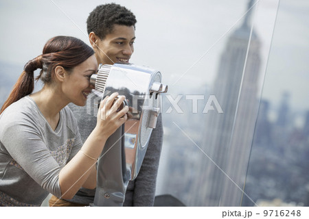 New York City. An observation deck overlooking the Empire State Building. A young couple looking through the telescope. 9716248