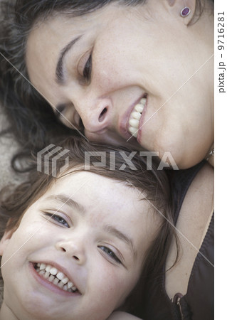 A close up of a mother and daughter lying with their heads together, smiling and laughing. A close up of a mother and daughter lying with their heads together, smiling and laughing. 9716281